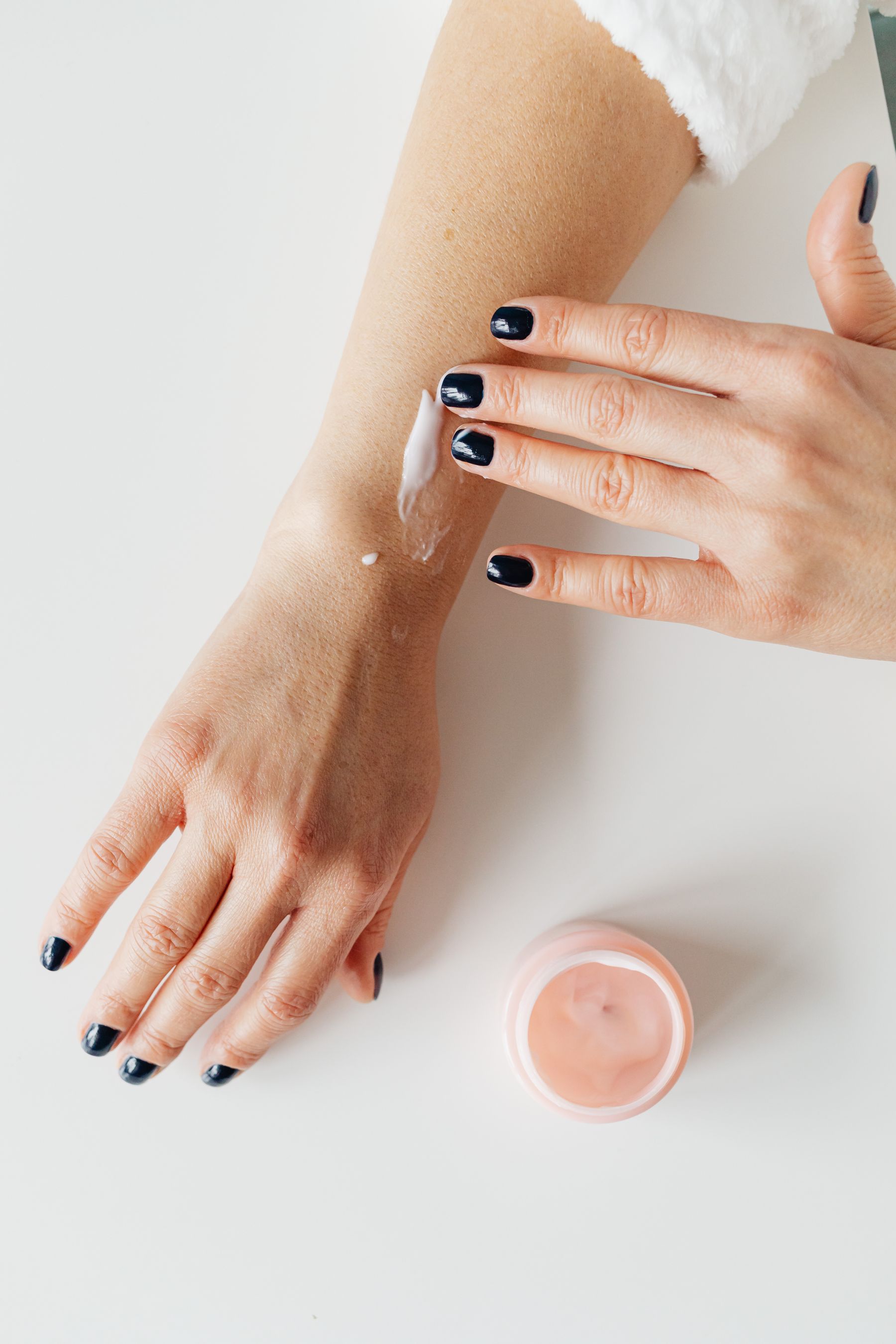 Fingers spreading a small amount of cream on a forearm