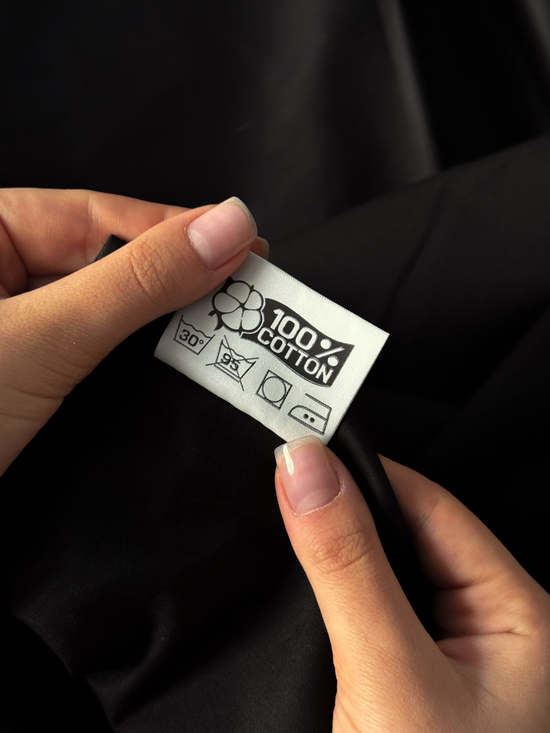Hands holding a 100 percent cotton garment label