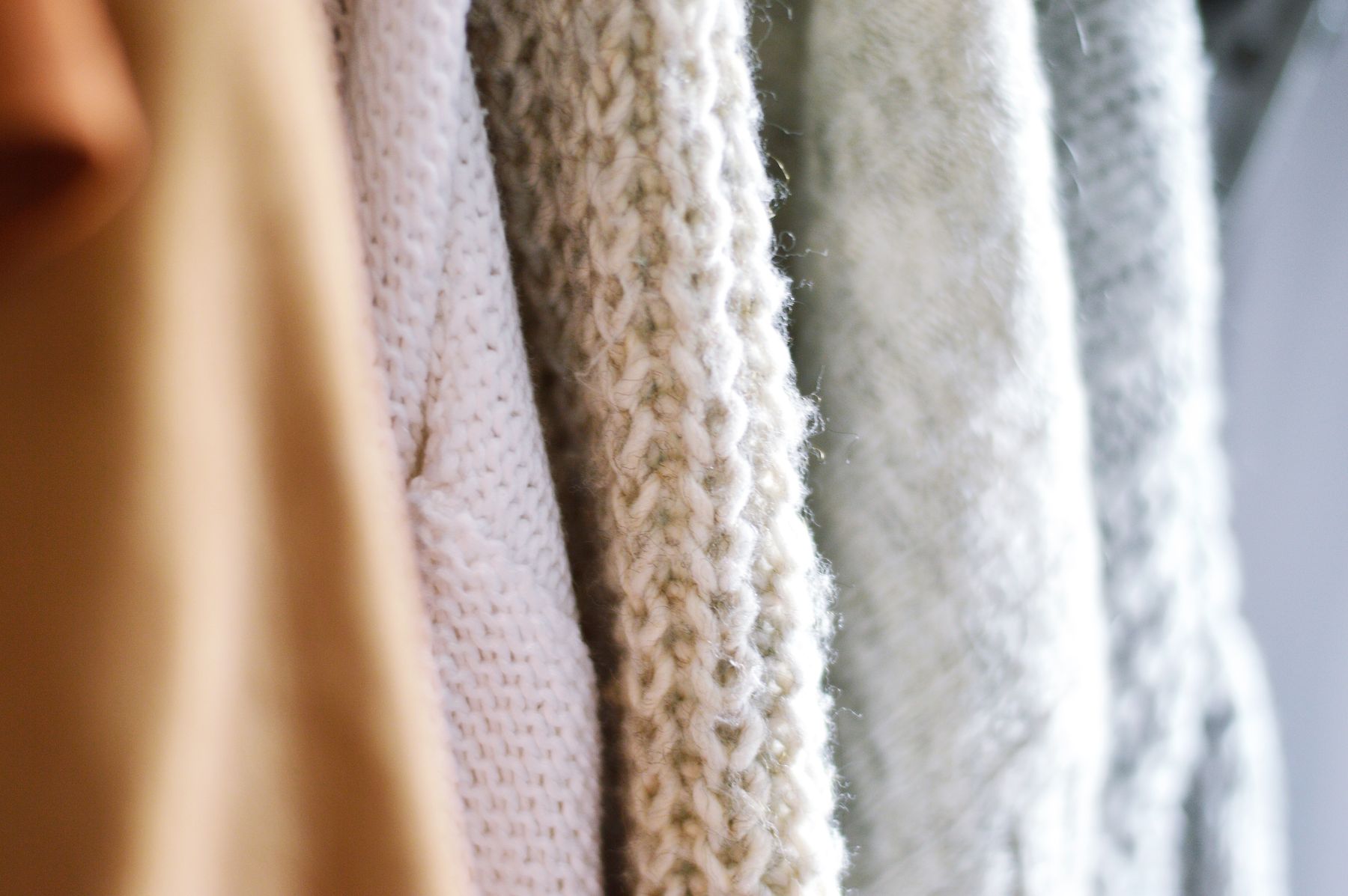 Close view of pale knitted garments with different stitch textures
