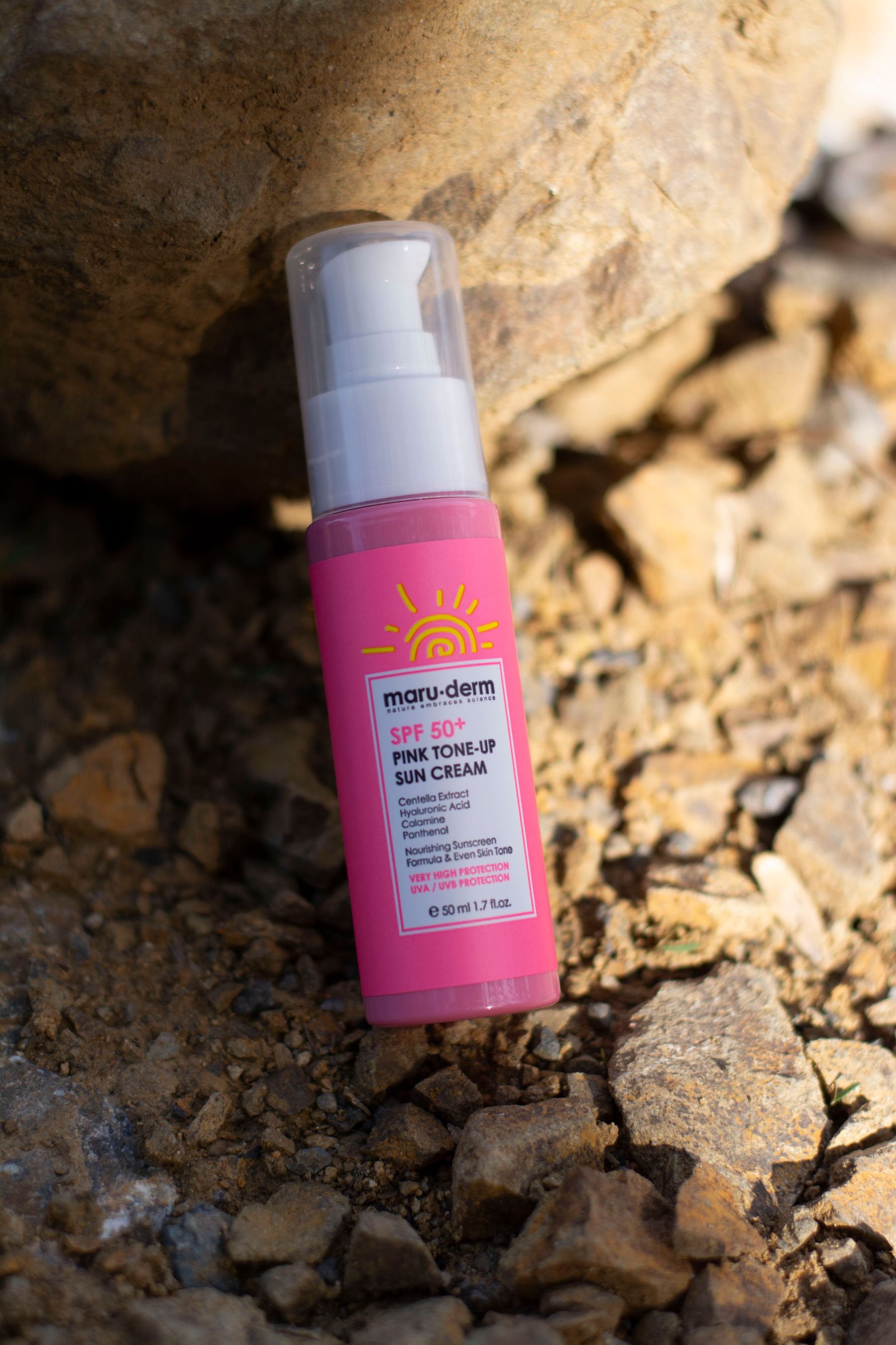 Pink SPF50plus suncream bottle against a rock