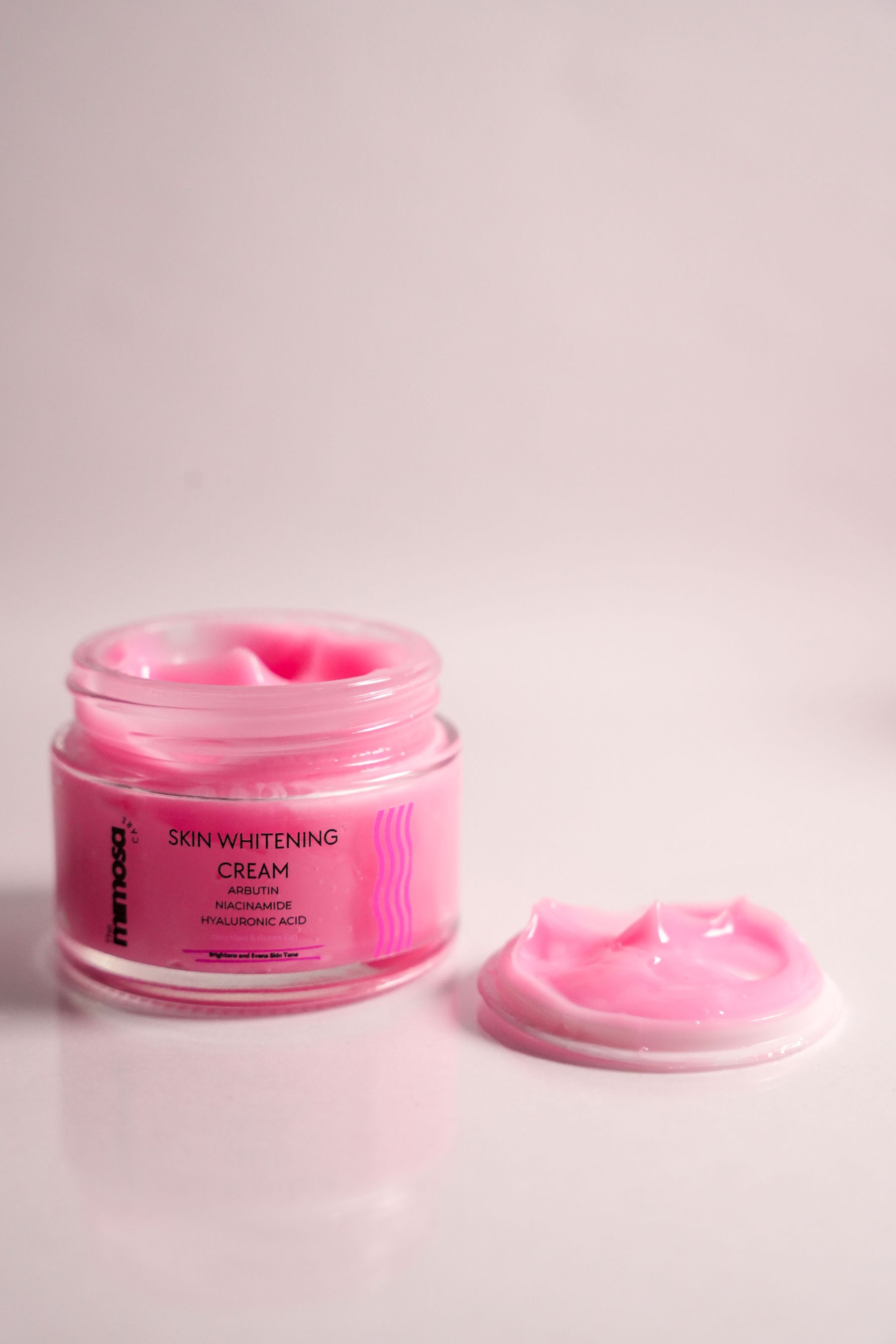 Open pink cream jar with skin-whitening wording on the label